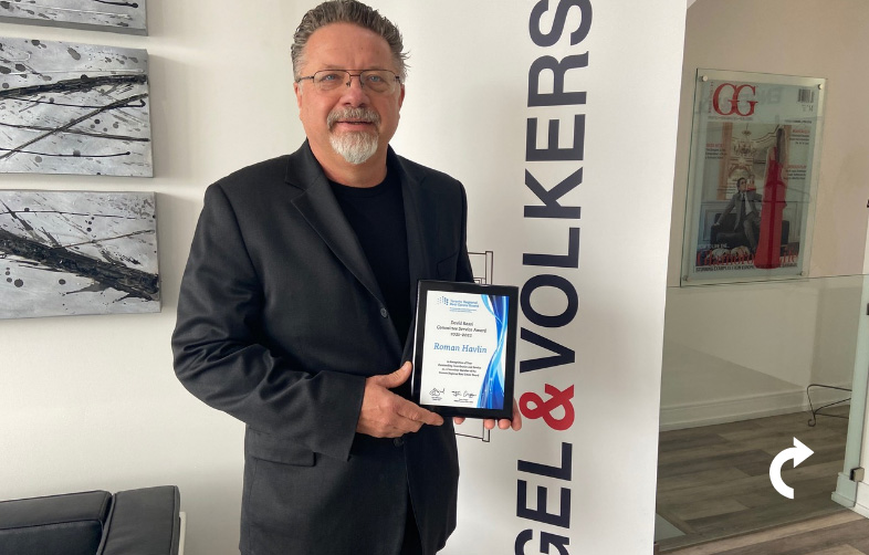 Roman Havlin smiling and holding his 2022 David Rossi Committee Service Award