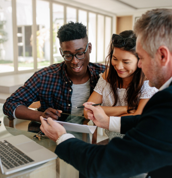 happy couple meeting with a male real estate agent about to sign an offer