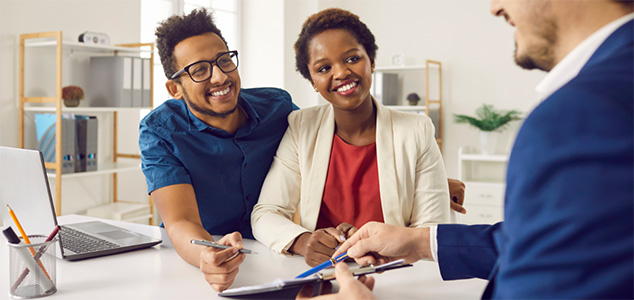 happy couple meeting with a male real estate agent.