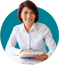 woman in white shirt sitting at a desk and smiling with a book in her hand, looking to camera